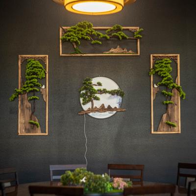 Decorative wall art with bonsai designs above a dining table.