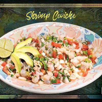 Shrimp Ceviche garnished with avocado sleces and a half of lime.