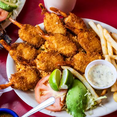 Breaded shrimp served with fries, avocado, and dipping sauce.