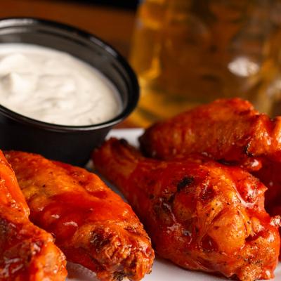 Spicy buffalo chicken wings with ranch sauce, close-up.