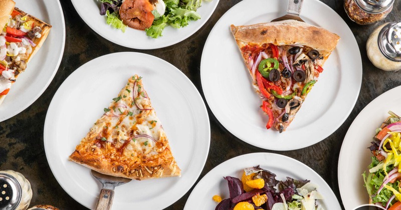 Table filled with delicious pizzas and salads