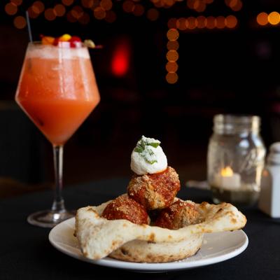 Grandma's Meatballs served in a pizza dough bowl, accompanied by a red cocktail.