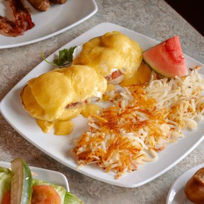 Eggs Bennedict served with hash browns and a slice of wetermelon.