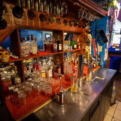 Back bar featuring a stainless-steel bar top and liquor bottles arranged on wooden shelves.
