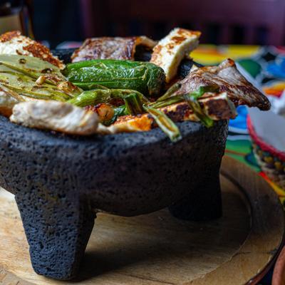 Molcajete with steak, grilled cheese, cactus, and a grilled jalapeno.