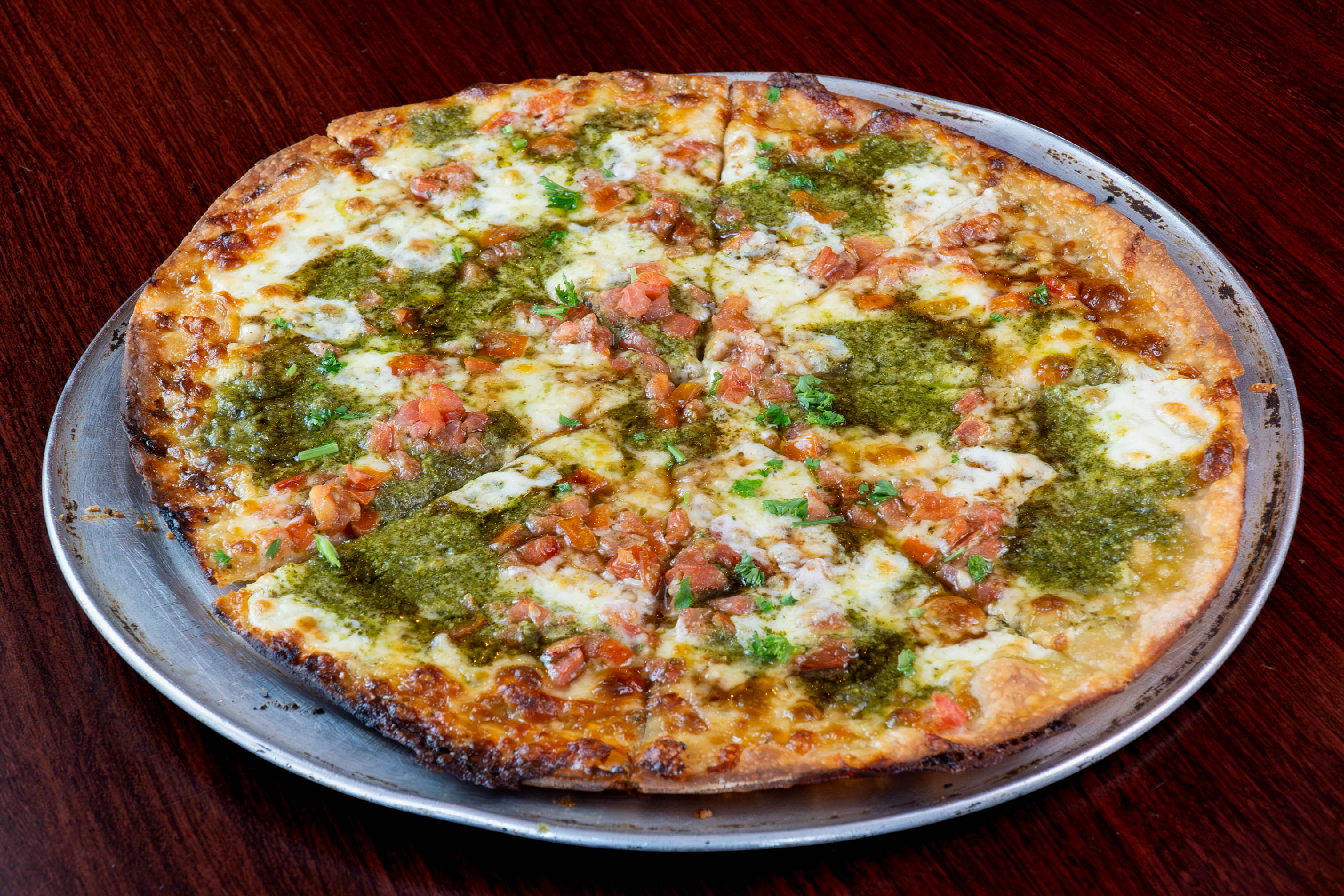 Caprese Pizza with mozzarella and tomato over a garlic aioli base, topped with balsamic and pesto drizzle