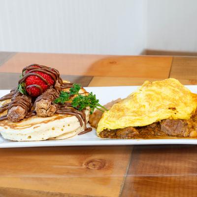 Pancakes with churros and chocolate drizzle beside a beef stew omelet.