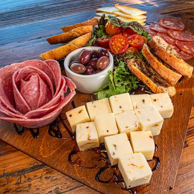 Charcuterie board with meats, cheeses, olives, and bread