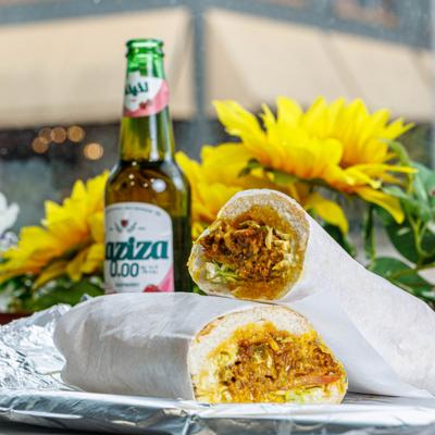 Chicken steak sub cut in half with a bottle of non alcoholic malt beverage.