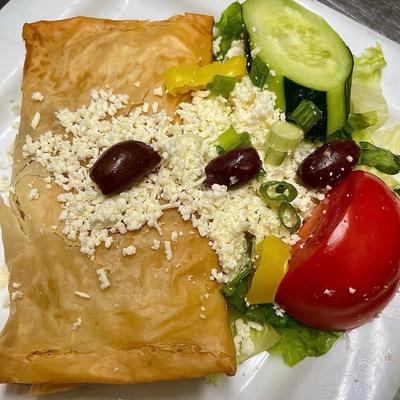 Filled phyllo pastry served with a side of Greek salad and grated cheese.