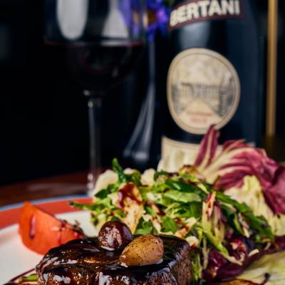 Steak topped with mushrooms beside leafy salad.