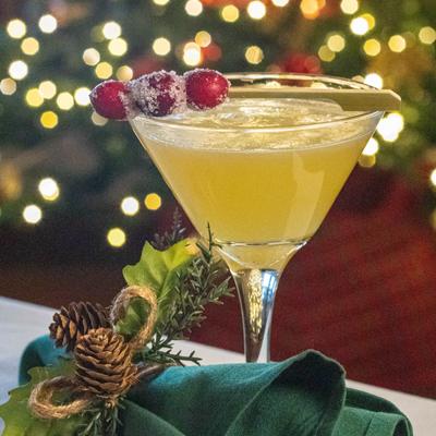 Christmas cocktail martini with sugared cranberries, on a festive table setting.