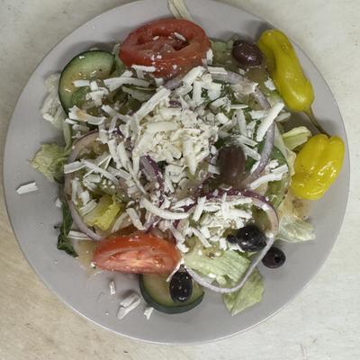 Greek salad with olives, cucumber, pepperonici, and shredded cheese.