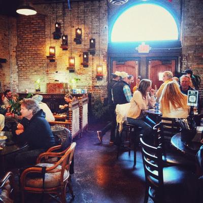 Interior featuring rustic brick walls, table seating and atmospheric lighting.