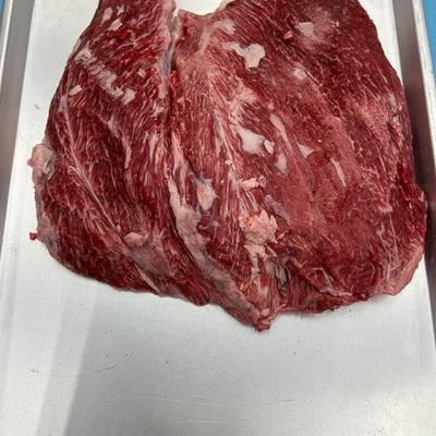 A close-up of a raw marbled beef cut on a silver tray.