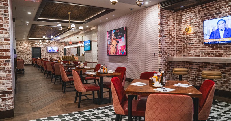 Interior, tables for four ready for guests, chandeliers, brick walls, TVs on the wall