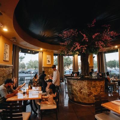 Restaurant interior with diners seated at tables in a room with decorative tree.