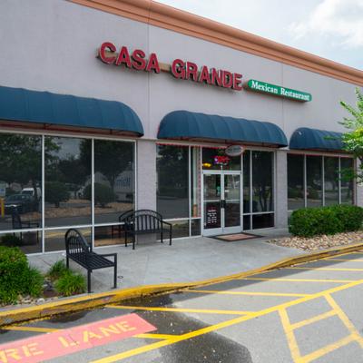 Exterior of Casa Grande Mexican Restaurant featuring blue awnings and outdoor seating.