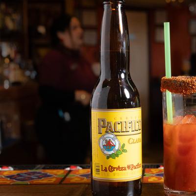 Michelada cocktail and a bottle of Mexican beer on a bar counter.