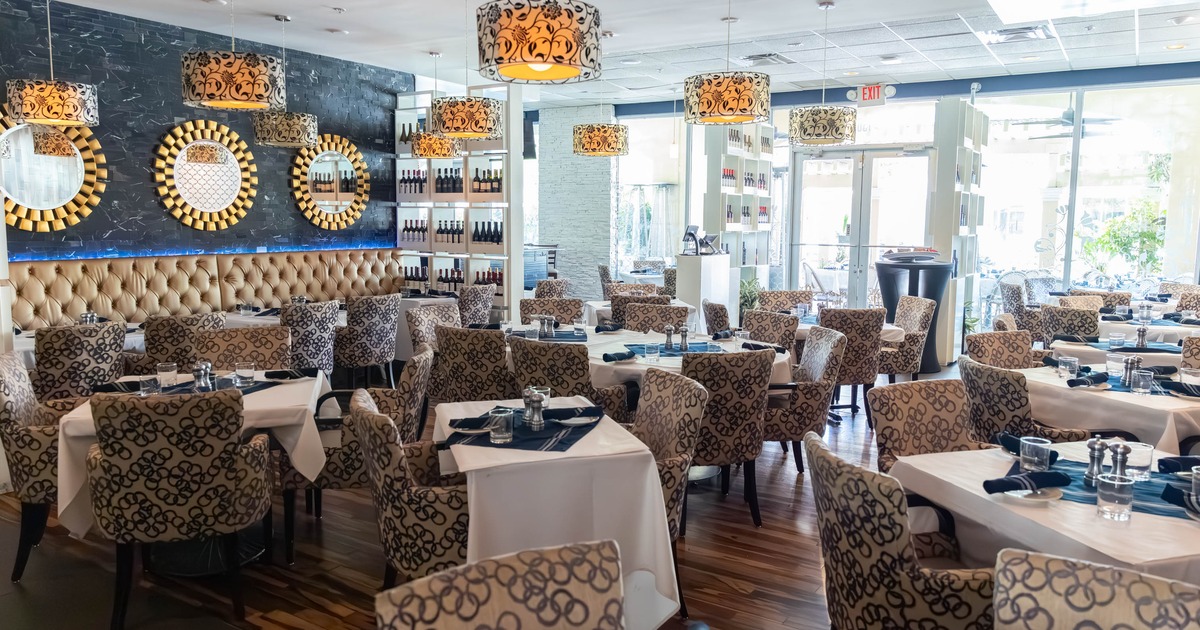 Spacious restaurant with elegant decor, circular mirrors and patterned chairs.