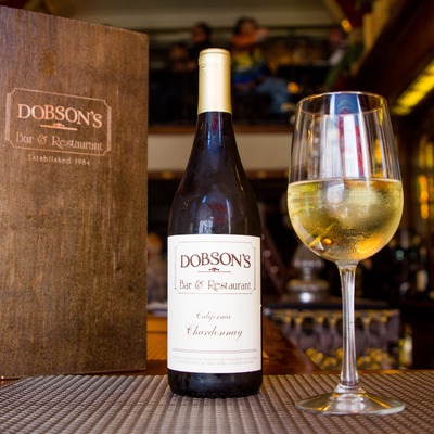 A bottle of Dobson's Chardonnay next to a filled white wine glass.