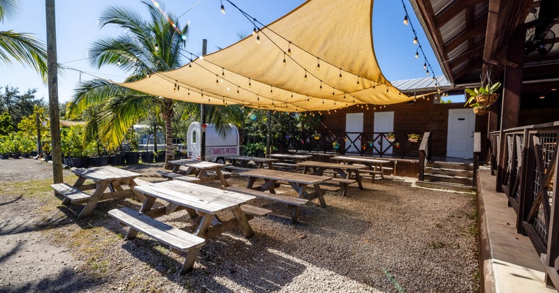 Exterior, partially covered seating area, wooden tables with benches, lanterns