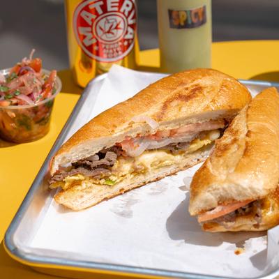 Steak sandwich with omelet, muenster cheese, tomato, onions, and garlic sauce.