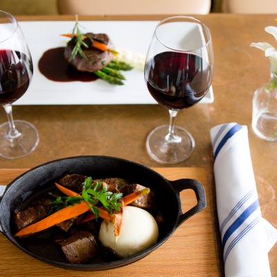 Braised beef short ribs plate and Filet Medallions , served with two glasses of wine.
