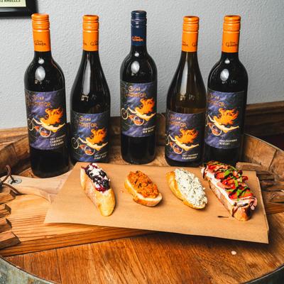 Crostini board in front of wine bottles.