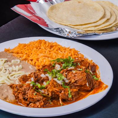 Birria plate with sides od rice, refried beans and tortillas.