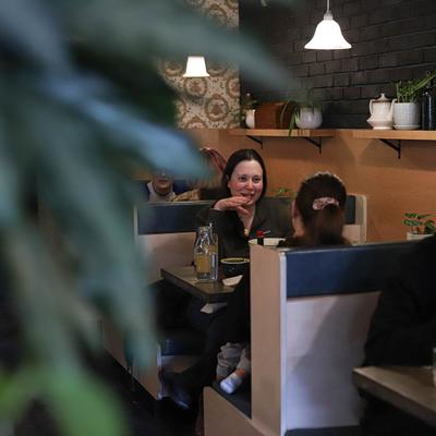 Guests seated at cozy booths, surrounded by plants.