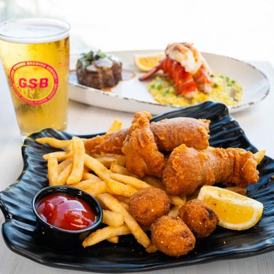 Fried seafood platter with fries, hushpuppies, and ketchup served with a beer.