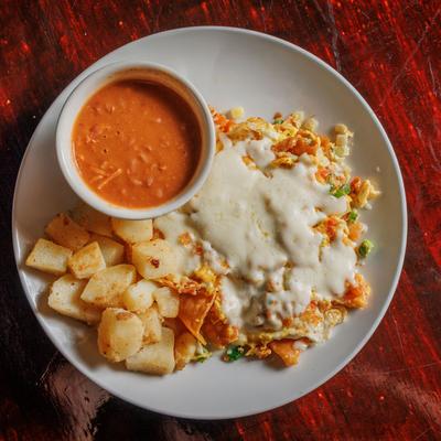Scrambled eggs with sauteed corn chips, jalapenos, tomato and onions, potatoes and beans