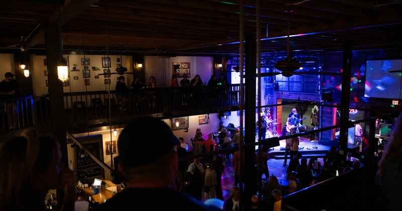 Crowded venue with live band performing on stage under colorful lights