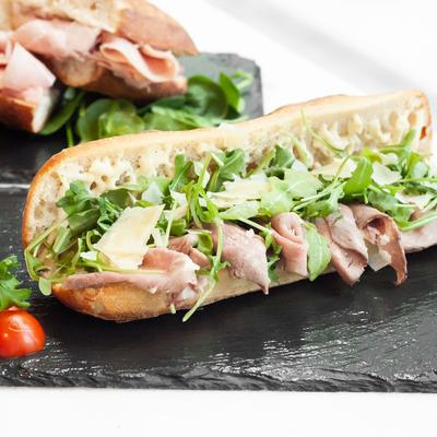 Sandwich with Angus roast beef, arugula, parmesan, and olive oil.