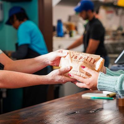 A person handing another person a bag of food.