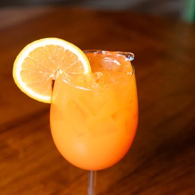 A refreshing orange drink, garnished with an orange slice, sits on a wooden table.
