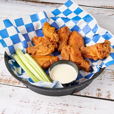 Chicken wings with ranch dressing and celery.
