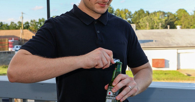 Person opening a bottle of beer outdoors