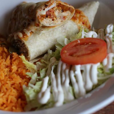 Nashville Hot Burrito served with rice and salad topped with sour creme.