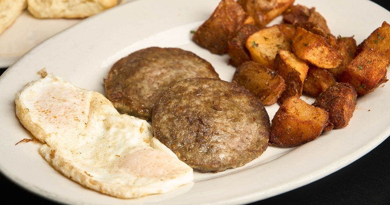 A plate with two fried eggs, home fries, and sausage