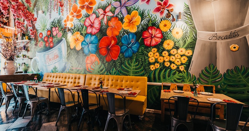 Interior, lined up dining tables and seating, a large mural on the wall