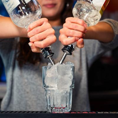 Bartender mixing drinks in a glass behind bar  counter.