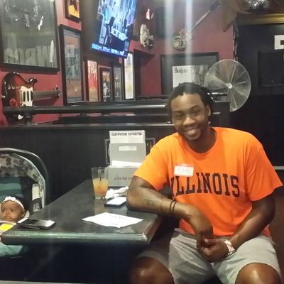 A smiling guy in an orange illinois shirt sitting and posing for a photo