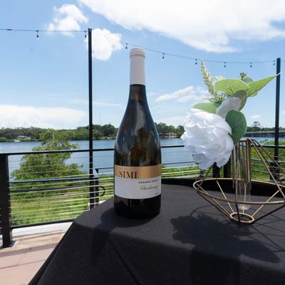 Chardonnay wine on a table with white flowers, a view of the river on a sunny day.