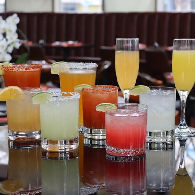 Various colorful cocktails displayed on a reflective surface.
