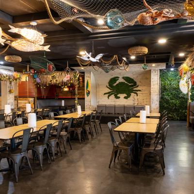 Restaurant interior with wooden tables, black chairs, and oceanic decor.