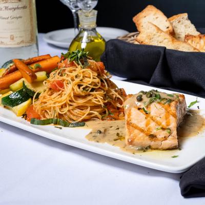 Grilled salmon served alongside angel hair pasta and roasted vegetables.