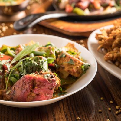 Tandoori chicken with various Indian dishes in the background.
