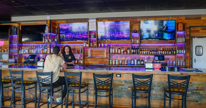 Bar, front view, stools, guest, bartender, drink rack